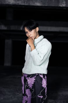 an asian man posing in a white sweater and a chain necklace around his neck in an old building