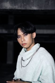 an asian man posing in a white sweater and a chain necklace around his neck in an old building