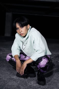 an asian man with black hair squats very masculine in an old building