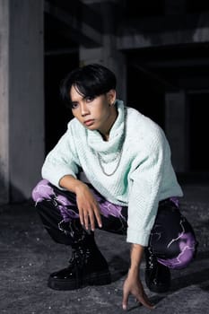 an asian man with black hair squats very masculine in an old building