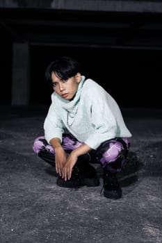 an asian man with black hair squats very masculine in an old building