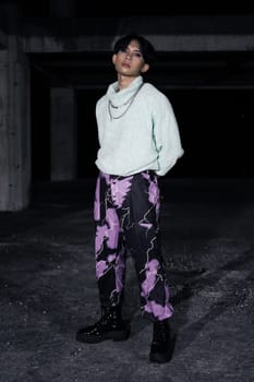 an asian man in black pants with a lightning pattern and a white sweater stands in a haunted building