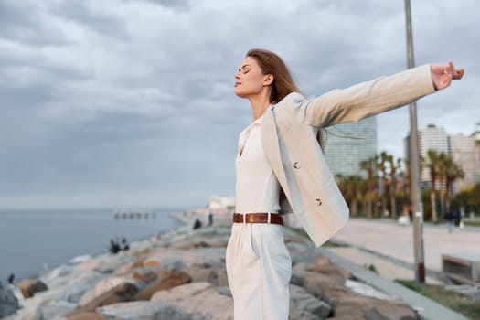 Empowered woman in a business outfit stands by the seaside, surrounded by urban landscape, showcasing confidence and tranquility. Perfect for business themes.