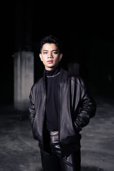 an Asian man wearing a leather jacket and black pants with a handsome face in an old building