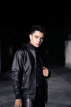 an Asian man wearing a leather jacket and black pants with a handsome face in an old building