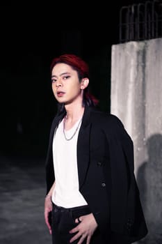 a red haired asian man wearing a white t shirt and black suit in an old building at night