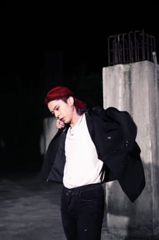 a red haired asian man wearing a white t shirt and black suit in an old building at night