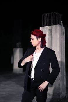 a red haired asian man wearing a white t shirt and black suit in an old building at night