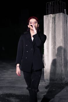 a red haired asian man wearing a white t shirt and black suit in an old building at night