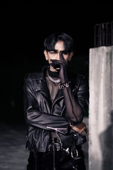 an asian man in a black leather jacket posing like a motorcycle gang in an old building