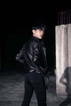 an asian man in a black leather jacket posing like a motorcycle gang in an old building