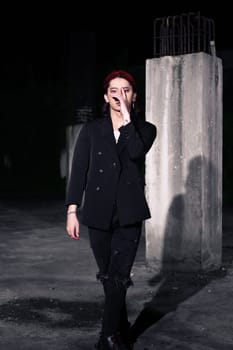 a red haired asian man wearing a white t shirt and black suit in an old building at night