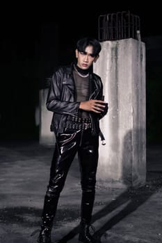 an asian man in a black leather jacket posing like a motorcycle gang in an old building
