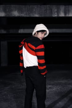 an Asian man with a striped red shirt and a chain necklace around his neck in an old building