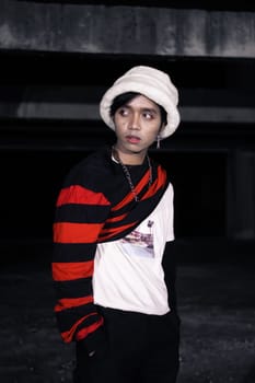 an Asian man with a striped red shirt and a chain necklace around his neck in an old building