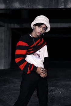 an Asian man with a striped red shirt and a chain necklace around his neck in an old building