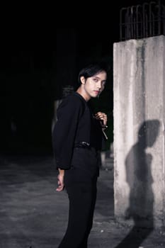 an Asian man is standing in black clothes and wearing makeup at night