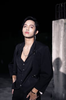 an Asian man wears a black suit with an open chest so it looks sexy at night