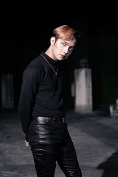 portrait of a blonde Asian man in a black sweater and black belt around his waist posing