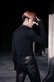 portrait of a blonde Asian man in a black sweater and black belt around his waist posing