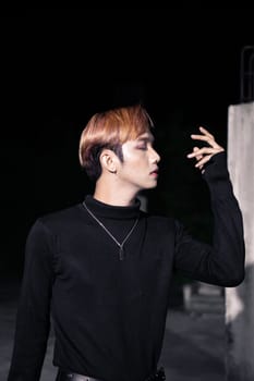 portrait of a blonde Asian man in a black sweater and black belt around his waist posing
