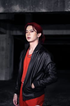 an asian man with red hair and a black jacket is posing in an abandoned building at night