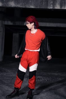 an asian man with red hair and a black jacket is posing in an abandoned building at night