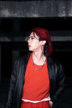 an asian man with red hair and a black jacket is posing in an abandoned building at night