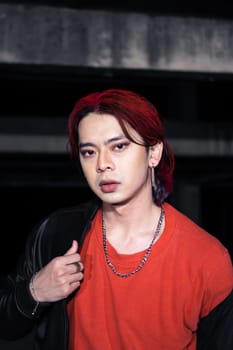 an asian man with red hair and a black jacket is posing in an abandoned building at night