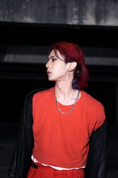 an asian man with red hair and a black jacket is posing in an abandoned building at night