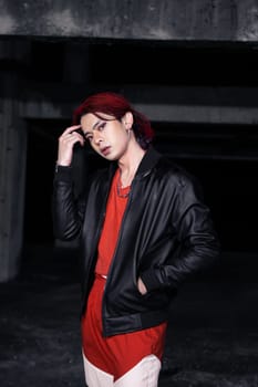 an asian man with red hair and a black jacket is posing in an abandoned building at night