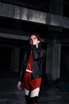 an asian man in a red shirt and earrings in his ears is standing in an abandoned building