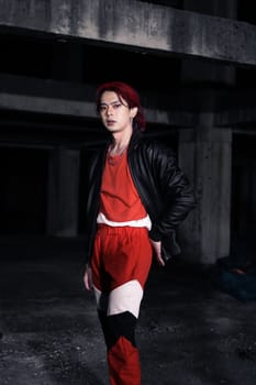 an asian man in a red shirt and earrings in his ears is standing in an abandoned building