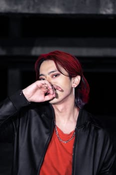 an asian man in a red shirt and earrings in his ears is standing in an abandoned building