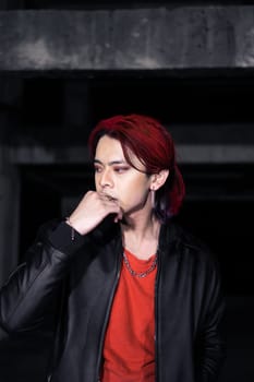 an asian man in a red shirt and earrings in his ears is standing in an abandoned building