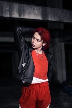 an asian man with red hair and a black jacket is posing in an abandoned building at night