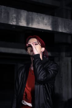 an asian man in a red shirt and earrings in his ears is standing in an abandoned building