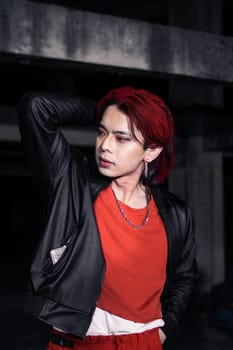 an asian man in a red shirt and earrings in his ears is standing in an abandoned building
