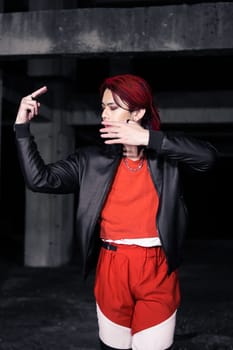 an asian man in a red shirt and black jacket posing with his hands in an abandoned warehouse
