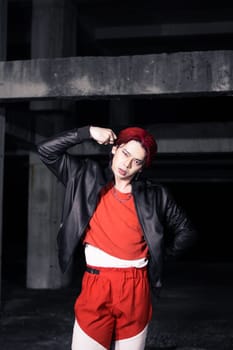 an asian man in a red shirt and black jacket posing with his hands in an abandoned warehouse