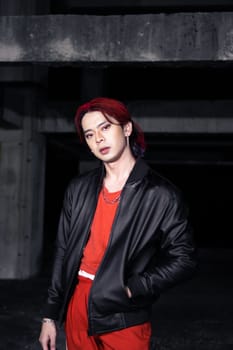 an asian man in a red shirt and earrings in his ears is standing in an abandoned building