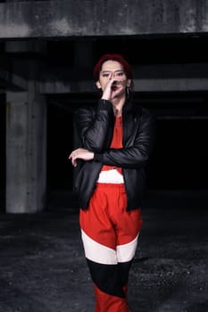 an asian man in a red shirt and black jacket posing with his hands in an abandoned warehouse