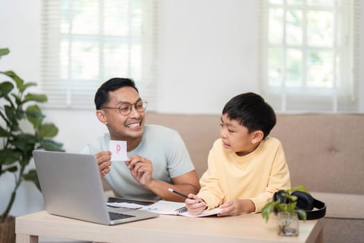 A cheerful father showing fun activity cards to his son during their homeschool session, making learning interactive.
