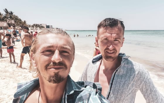 Male tourists men best friends guys are posing for a photo selfie model and having fun swimming on the mexican Caribbean beach in Playa del Carmen Quintana Roo Mexico.