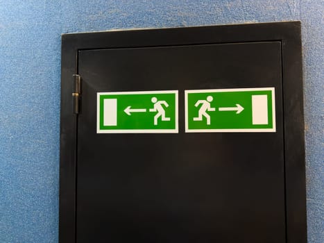 Universal exit signs with running figure and directional arrows illustrate internationally recognized emergency guidance system, offering nonverbal clarity across cultures in public buildings