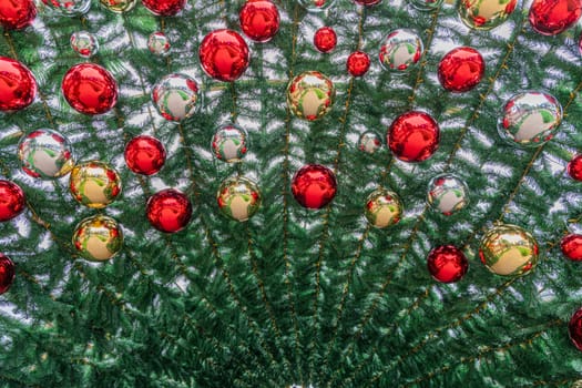 Bright red and gold ornaments adorn an evergreen tree, creating a festive atmosphere. The circular decorations reflect light, enhancing the holiday spirit during winter celebrations.