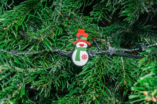 A vibrant Christmas tree adorned with a cheerful snowman ornament, sparkling lights, and lush green branches, evoking a festive atmosphere during the holiday season.
