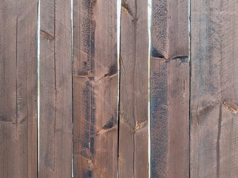 Close-up view of a wooden fence showcasing various shades of brown. Each slat exhibits unique patterns and textures, revealing the natural beauty of the wood grain.