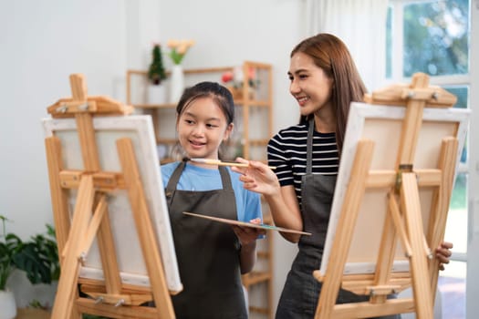 A mother and daughter enjoying a painting session, bonding over creativity and laughter while learning together at home.