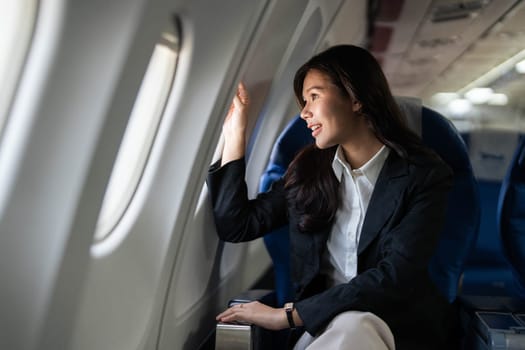 A thoughtful businesswoman gazing out of an airplane window, reflecting on her journey while traveling for work.